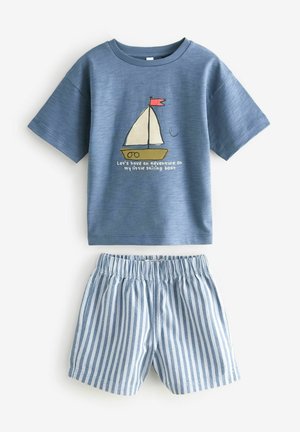 Zila kokvilnas T-krekls ar jahtas grafikā un tekstu, kombinēts ar ziliem un baltajiem svītrainiem šortiem. Ikdienišķs, ērts piegriezums bērniem.