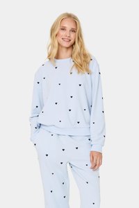 Sudadera de color azul claro y pantalones a juego con un corte relajado, que presentan pequeños patrones de corazones negros en todo su diseño. Tejido suave y puños acanalados.