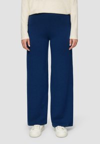 Navy wijde broek gemaakt van zachte, gestructureerde stof, met een elastische tailleband. Gecombineerd met witte sneakers.