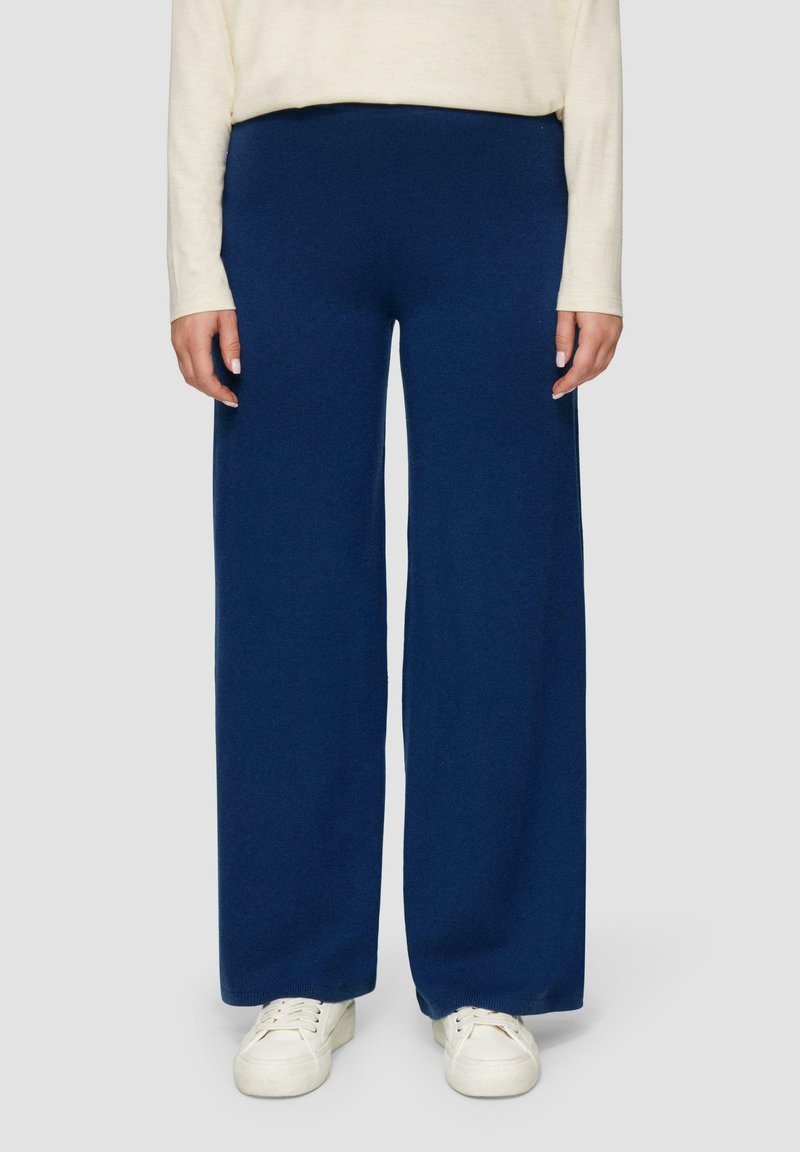 Navy wijde broek gemaakt van zachte, gestructureerde stof, met een elastische tailleband. Gecombineerd met witte sneakers.