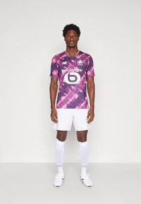 Ljubičasta i ružičasta nogometna majica s uzorkom, kratkih rukava, bijele kratke hlače i čarape. Sadrži logo sponzora i marku na prednjoj strani.