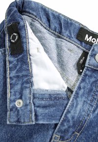 Pantalones vaqueros de mezclilla azul con un forro ligero, que presentan una etiqueta con la inscripción "128 cm", botones metálicos y costuras reforzadas a lo largo de las costuras.