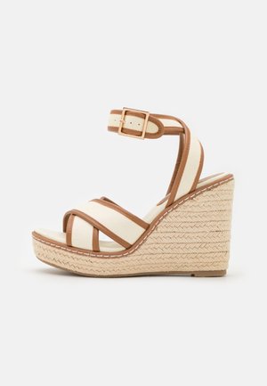 Beige og brun kile-sandal med ankelrem, spænde-lukning, krydsede forreste stropper og flettet espadrille-platformsål.