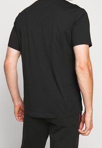 Sort bomulds T-shirt med korte ærmer og rund hals. Enkel, let design med en glat tekstur og ingen synlige mønstre.