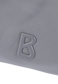 Sivina tkanina z teksturirano površino, ki vsebuje izrazito, oblikovano sivo črko "B" kot oblikovni poudarek.