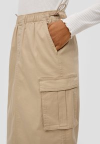 Beige cargorok met een elastische tailleband, zijzak en een opvallende patchzak met plooidetail. Gladde katoenkwaliteit.