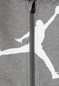 Grauer Reißverschluss-Hoodie mit einem auffälligen weißen Silhouetten-Design. Hergestellt aus weichem Material mit strukturierter Oberfläche, verfügt über einen robusten Reißverschluss.