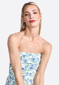 Strapless jurk met een bloemenpatroon in blauwe en groene tinten, met een aansluitend lijfje en gelaagde rok, gemaakt van lichte stof.