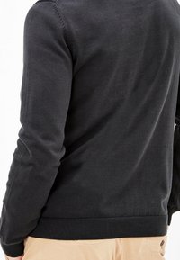 Schwarzer Baumwollpullover, slim fit, Rundhalsausschnitt, gerippter Saum und Bündchen, glatte Textur, schlichtes Design, keine sichtbaren Logos oder Muster.