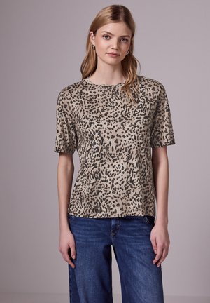 Top a maniche corte con stampa leopardata in beige e nero, realizzato in un tessuto morbido con un fit rilassato, abbinato a jeans blu.