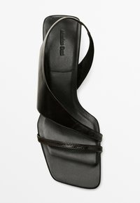 Schwarze Ledersandale mit quadratischer Zehenpartie, die über Kreuz gewirkte Riemen und eine strukturierte Sohle verfügt. Minimalistisches Design mit schlanker Silhouette.