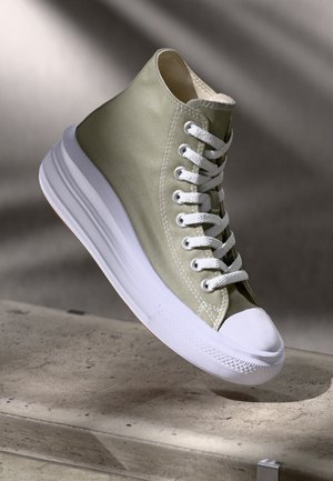 Sneaker alta in tela verde oliva con suola e lacci bianchi. Presenta una punta arrotondata e pannelli laterali testurizzati.