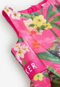 Ärmelloses Blumenkleid mit einer pinken Netzstruktur, lebendigen Farben und einem Akzentband mit Logo. Ausgestattet mit verschiedenen Blumenmustern.