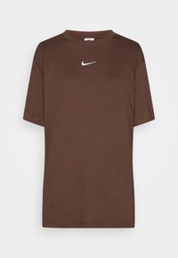 Hnědé bavlněné tričko s kulatým výstřihem a krátkým rukávem. Na hrudi se nachází bílé logo Nike, má hladkou strukturu a základní střih.