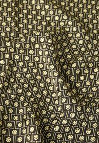 Tume kangas, millel on korduv muster beežidest tennispallidest ristkülikukujulistes raamides, voldikute ja kortsudega.