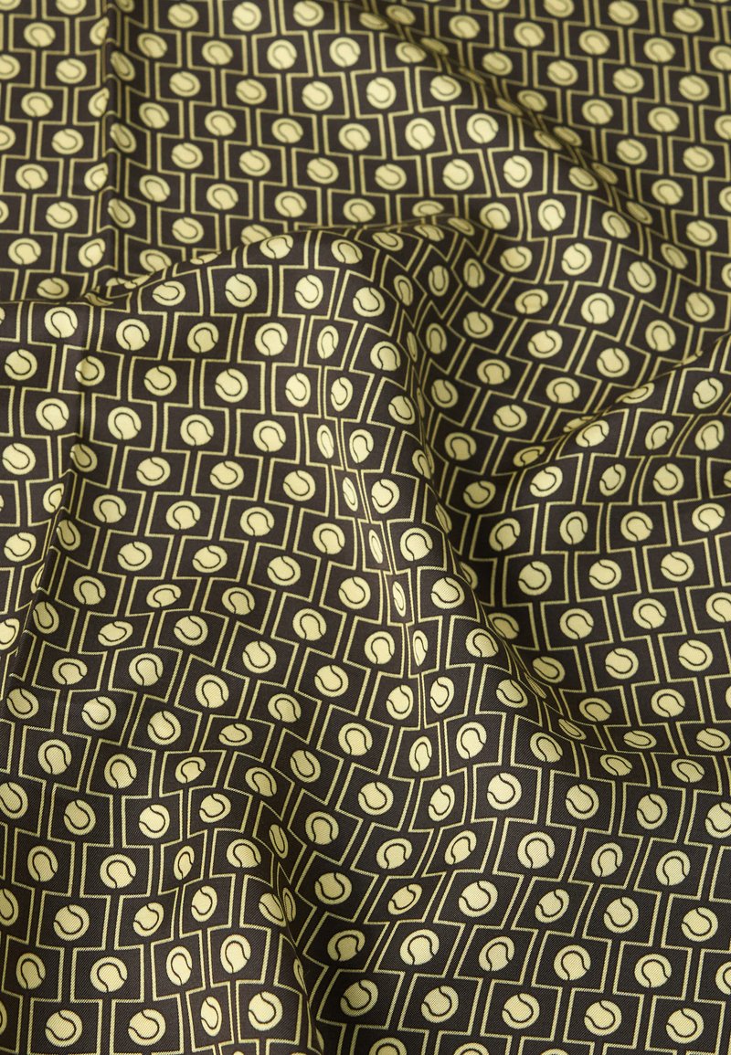 Dunkler Stoff mit einem sich wiederholenden Muster aus beigefarbenen Tennisbällen in rechteckigen Rahmen, drapiert mit sichtbaren Falten und Knicken.
