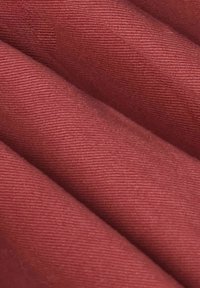 Gros plan sur un tissu rose poussiéreux plié avec une texture fine en côtes visible et une apparence douce et lisse.