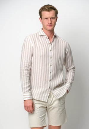 Camisa de manga larga a rayas en color beige claro y blanco, con un frente abotonado, cuello clásico y corte slim. Combinada con pantalones cortos beige.