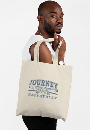 Beżowa torba bawełniana z niebieskim napisem graficznym "JOURNEY" oraz "FAITHFULLY," z skrzydlatym emblemem i rokiem "1983." Dwie solidne rączki.