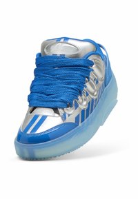 Silberner und blauer Sneaker mit dicken blauen Schnürsenkeln, reflektierenden Streifen und durchsichtiger blauer Sohle, seitlich vorne betrachtet.