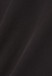 Tissu en coton noir avec une texture lisse, présentant un léger éclat et un motif côtelé fin, plié en angle.