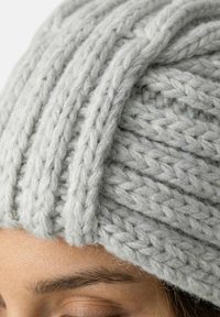 Grå strikket hue med et tekstureret ribmønster, lavet af tykt garn, med en tæt pasform og blødt, fnugget udseende.