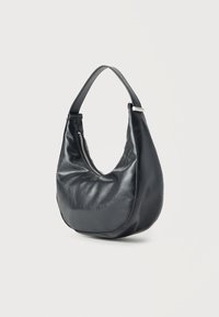 Μαύρη δερμάτινη τσάντα ώμου με φαρδιά λουράκι και εμφανές ασημί φερμουάρ στη μία πλευρά, εκτεθειμένη σε ουδέτερο φόντο.