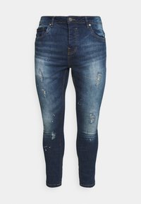 Dark blue denim jeans with a slim fit, featuring light distressing, faded areas, and subtle stitching details. Classic five-pocket design.