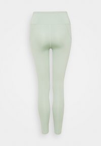 Leggings verde chiaro con vita alta, texture liscia e design aderente. Presentano cuciture laterali e un taglio alla caviglia.