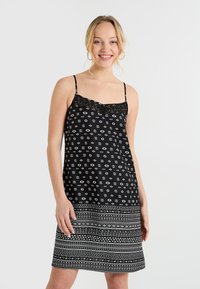 Vestido negro sin mangas con borde de encaje, con un patrón de ojos en blanco y un dobladillo estampado. Tejido suave con un ajuste holgado.