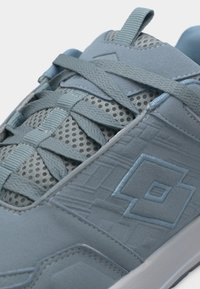 Κοντινό πλάνο ανοιχτό μπλε αθλητικού παπουτσιού με πλεκτό ύφασμα, κορδόνια σε σταυρωτό σχέδιο, κεντημένο λογότυπο και υφή σε πλαϊνή επιφάνεια.