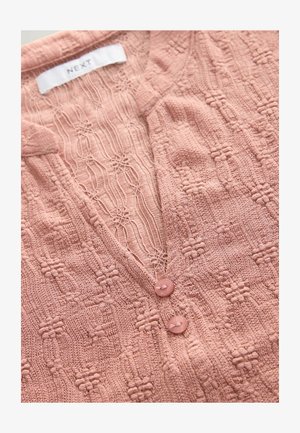 Cardigan en tricot rose avec un motif texturé, doté d'un col en V et de deux boutons au niveau de l'encolure, étiqueté "NEXT" sur une étiquette.
