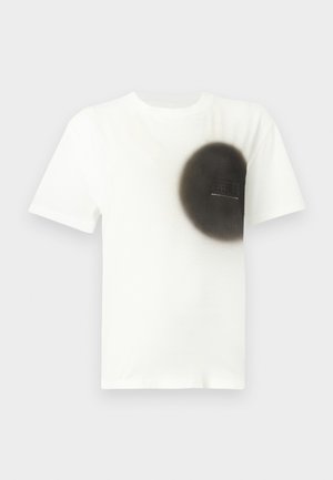 White short-sleeve t-shirt with a large black spray-painted circle on the left chest area and a small rectangular label within the circle.