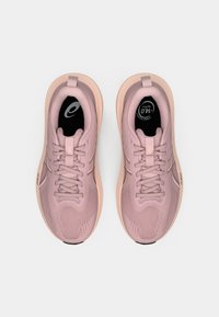 Par de zapatillas deportivas rosas con suelas de melocotón claro, parte superior de malla, cierre de cordones y plantillas negras, mostradas desde arriba sobre un fondo blanco.