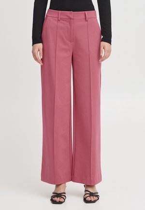 Wide-legged trousers in a soft pink fabric, featuring pleats, a high waistband, and a smooth texture, paired with strappy black sandals.