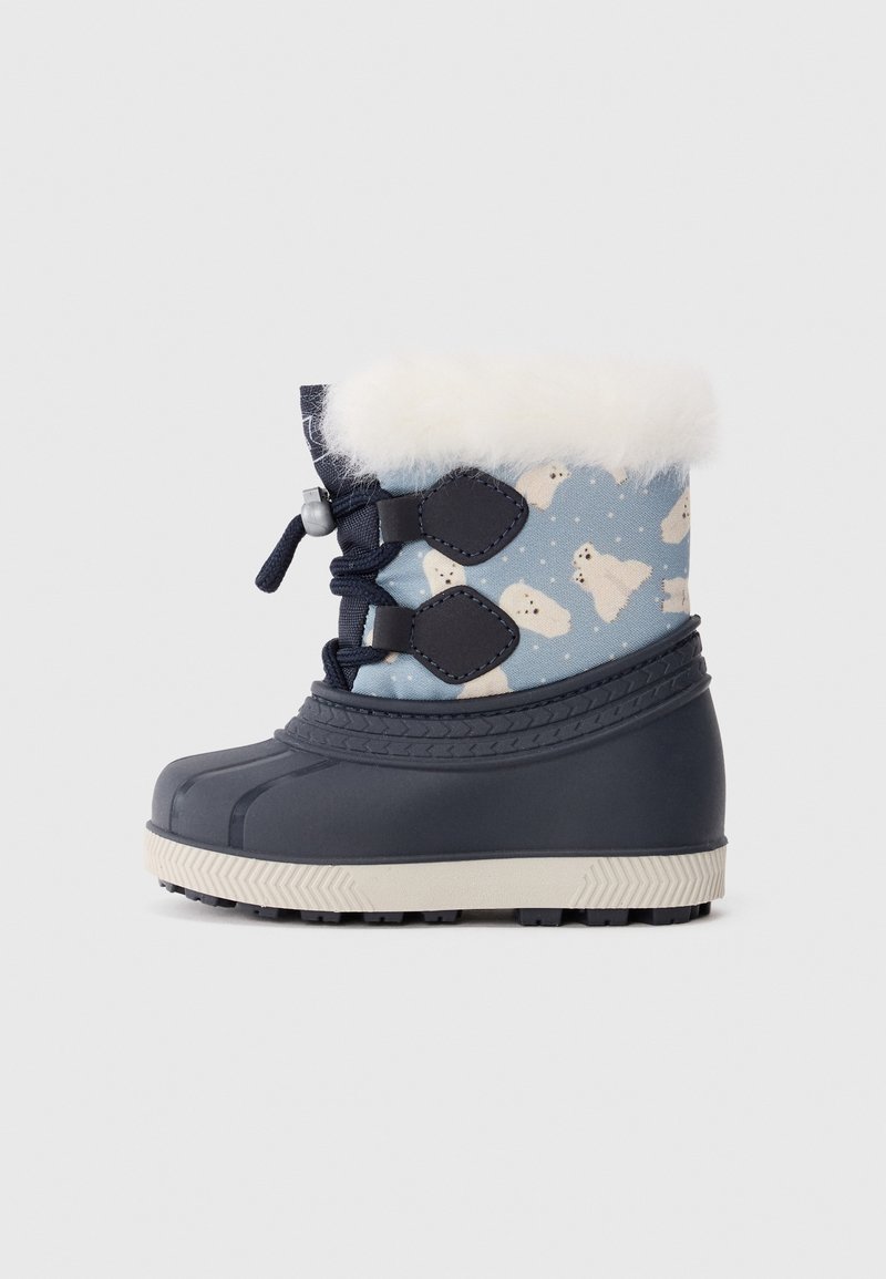 Botte d'hiver enfant avec semelle en caoutchouc bleu marine, dessus en tissu bleu décoré d'ours polaires, garniture en fausse fourrure blanche et fermeture à lacets sur fond blanc.