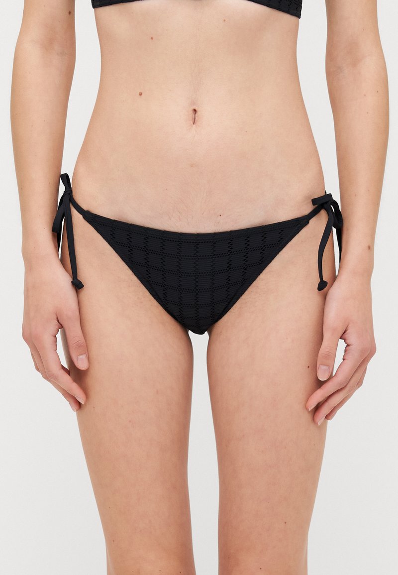 Bas de bikini noir avec un motif à carreaux texturé, des liens latéraux réglables et un design taille basse.