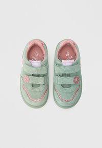 Green suede children's shoes with pink accents, mesh panels, double hook-and-loop straps, and a floral embellishment on the side.