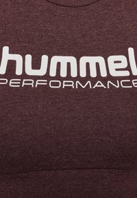 Vinröd sweatshirt i bomullsblandning med stor vit text "hummel PERFORMANCE" över framsidan, med en slät yta.