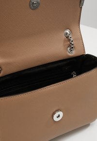 Borsa a tracolla di colore nocciola con finitura liscia, dotata di chiusura a scatto in argento, dettagli in catena e un compartimento interno con zip nera.