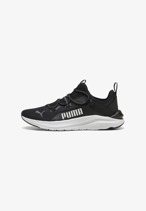 Musta urheilukenkä, jossa on teksturoitu verkkopinta, kontrastivärinen valkoinen kumipohja, joustavat nauhat ja "PUMA"-brändäys sivulla.