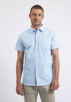 Chemise à manches courtes, bleu clair, avec un bouton et une poche, présentant un motif texturé subtil et un design de col classique.