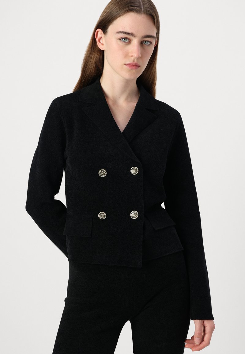 Schwarze doppelte Blazerjacke mit taillierter Passform, verfügt über silberne Knöpfe, zwei Fronttaschen und einen weichen, strukturierten Stoff.