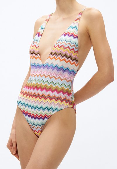 Kolorowy jednoczęściowy strój kąpielowy z wzorem w zygzaki, głębokim dekoltem w serek, regulowanymi ramiączkami i wysokimi wycięciami na nogi. Główne kolory to niebieski, różowy i pomarańczowy.