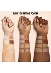 Tres brazos mostrando muestras de polvo fijador Evolution en varias tonalidades. Las muestras incluyen tonos claros a oscuros etiquetados del 1 al 5, con tonos rosa y amarillo.
