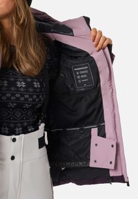 Wasserfeste pinkfarbene Jacke mit schwarzem Futter, ausgestattet mit einer Innentasche aus Netzstoff und Etiketten. Akzentuiert mit Druckknöpfen und einem Logo entlang dem inneren Saum.