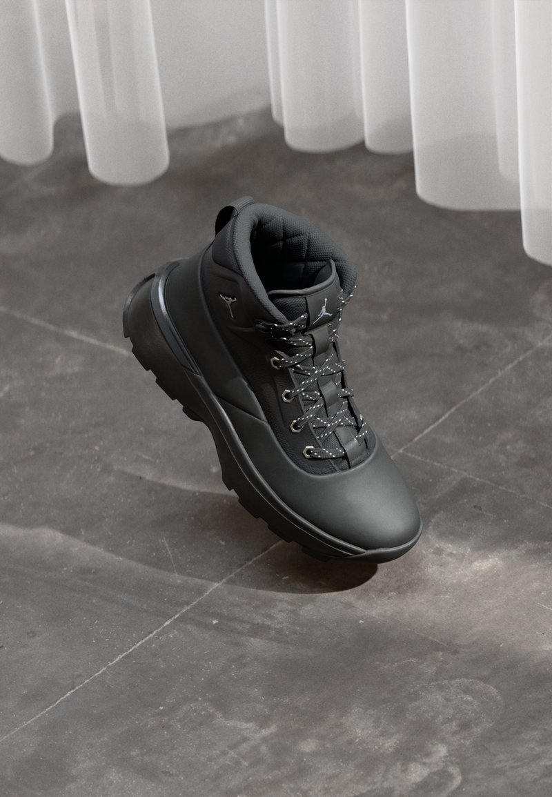 Czarne outdoorowe buty z wyściełanym kołnierzem, skórzaną cholewką o teksturowanej powierzchni, płaskimi sznurówkami z białymi akcentami oraz solidną gumową podeszwą.