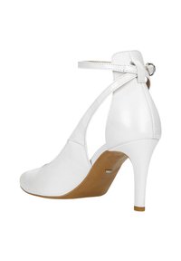 Scarpa bianca con tacco alto, punta affusolata, cinturino alla caviglia, finitura in pelle lucida e suola color tan. Presenta un design elegante e minimalista.