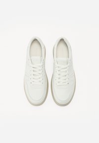 Chaussures blanches en cuir avec un bout arrondi, des lacets plats et une semelle texturée. Présente des coutures minimales et une finition lisse.