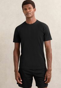 Tricou negru cu mânecă scurtă, fabricat dintr-un material moale, având un design clasic cu guler rotund și o textură simplă, netedă.
